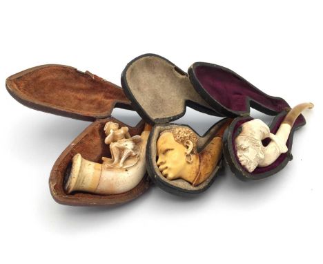 A Meerschaum pipe, 19th century, carved with a Moor wearing a tasselled hat, length 12cm, another similar pipe and another ca