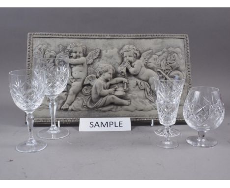 A quantity of clear glass pedestal drinking glasses, including four brandy balloons, a composition plaque with cherubs design