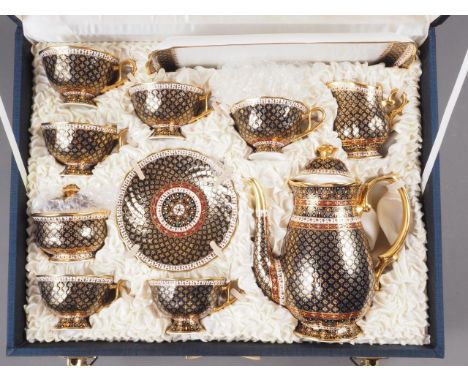 A Thai bone china coffee set with crimson and gilt decoration on a black ground, eighteen pieces including tray, in fitted bo