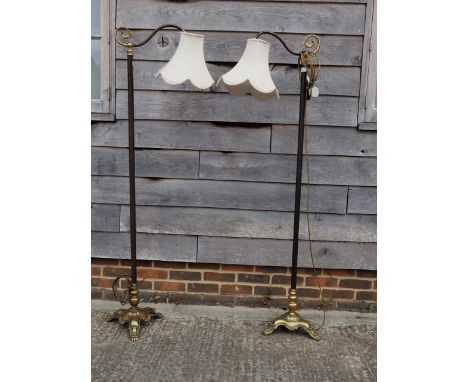A pair of early 20th century standard lamps with scrolled single light, on tripod brass supports, 65 1/2" high 
