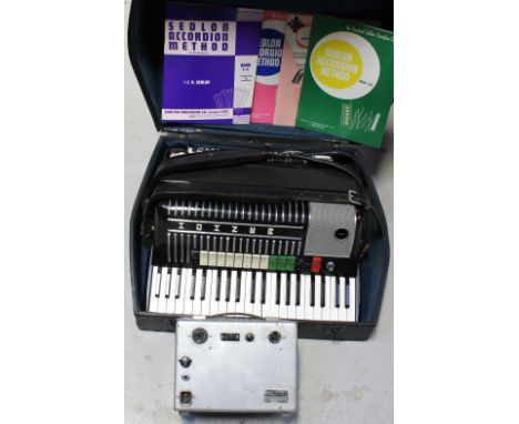 A cased Hohner piano accordion, music books, and miniature amplifier.
