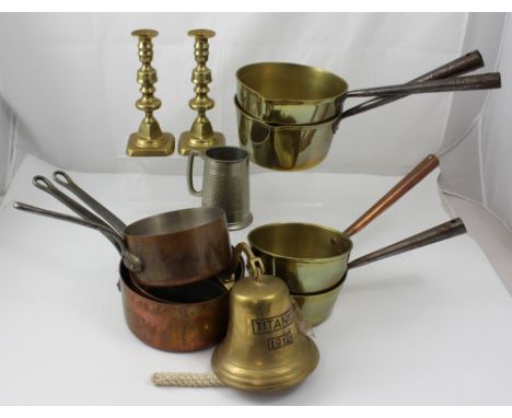 A collection of vintage brass and Ville Dieu copper saucepans, a pair of brass candlesticks, a replica Titanic bell, and a pe