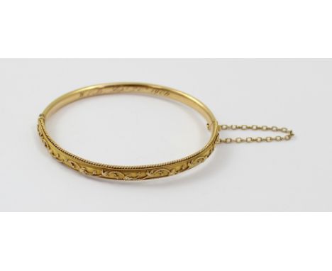 A 15ct yellow gold bangle marked '625' to the inside shank and with applied trailing frond decoration, approx 7.5g.