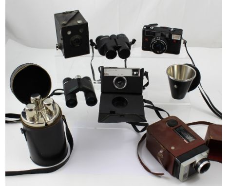 A black cylindrical cased set of three triangular shaped decanters, a cased set of metal beakers, a quantity of vintage camer