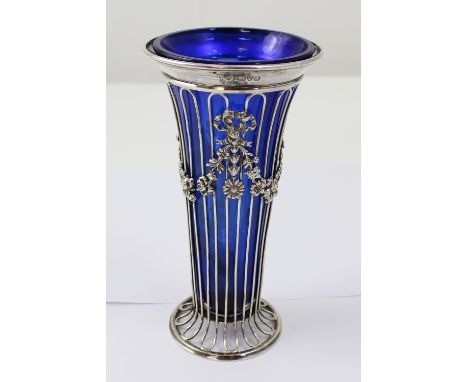 A silver wirework and blue glass lined trumpet vase decorated with ribbon bows, festoons of flowers and harebells, Haseler Br