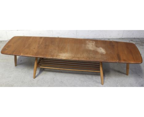 An Ercol drop leaf coffee table in golden stain supported on turned beech legs with magazine shelf stretcher, width when exte