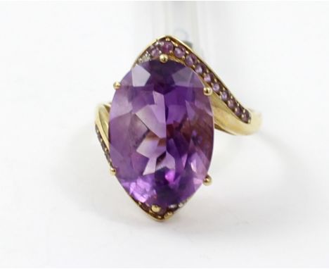 A 9ct gold ladies' dress ring set with a large oval amethyst-coloured stone, with smaller amethyst-coloured stones to the ban