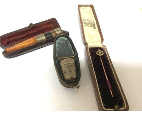 A vintage gold tie pin set with ruby sapphire and seed pearl a silver thimble and a cigarette holder (3)