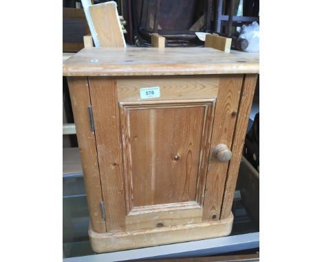 A pine bedside cabinet, a wooden shelf and a white wall mounting towel rail. 