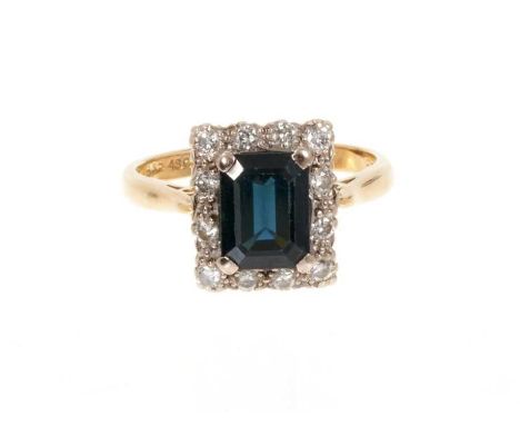 Sapphire and diamond cluster ring with a rectangular step cut blue sapphire measuring approximately 8mm x 6mm surrounded by a