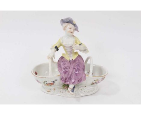 A Meissen double salt cellar, circa 1770, modelled as a female figure sat between two baskets, polychrome decorated, crossed 