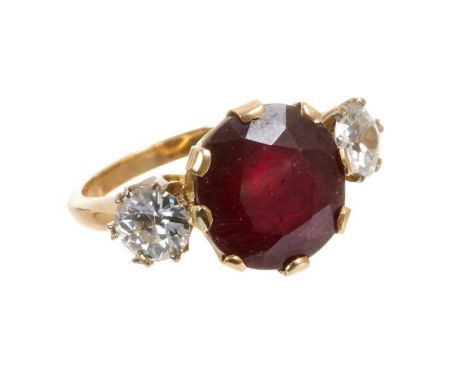 Ruby and diamond three stone ring with an oval mixed cut ruby measuring approximately 12mm x 11.5mm x 7.25mm flanked by two o