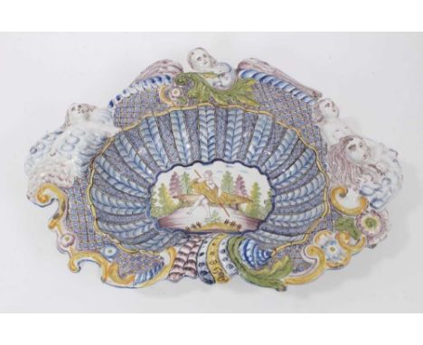 A late 18th/early 19th century German faience shell shaped basin, the centre with figural panel the outside moulded with cher