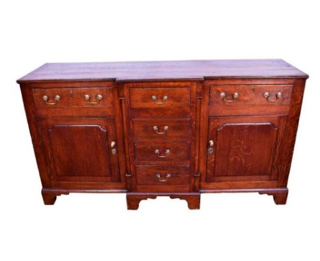 George III oak breakfront dresser base, with bank of four central drawers flanked by two frieze drawers with panelled cupboar