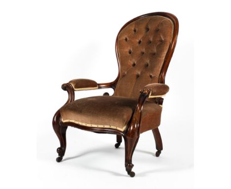 A Victorian mahogany framed spoon button back open armchair. With padded arms and scrolled carved decoration, over a stuffed 