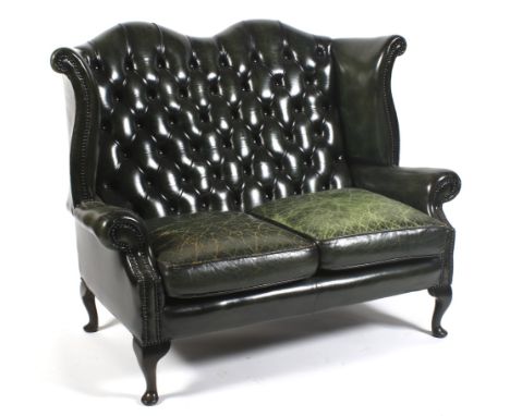 A Georgian style button back green leather sofa, 20th century. With high arched wing back, studded and with drop-in green lea