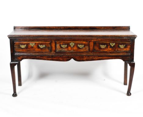 A Georgian oak dresser base. With moulded gallery and top above three frieze drawers, with shaped apron, on two front cabriol