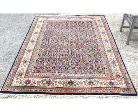 A large 20th century rug. Woollen blend, the central panel featuring a floral design on a blue ground, surrounded by multiple
