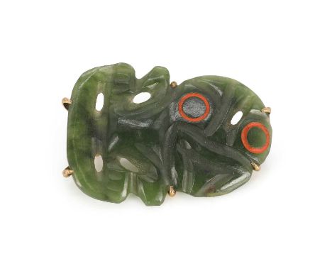 A New Zealand jade tiki brooch, carved jadeite, with red enamelled eyes, with 9ct gold backing and brooch fitting, measuring 