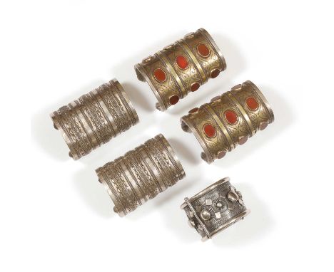 Four Turkoman silver bracelets and a silver Sudanese bangle, comprising:two Turkoman silver gilt carnelian bracelets,with row