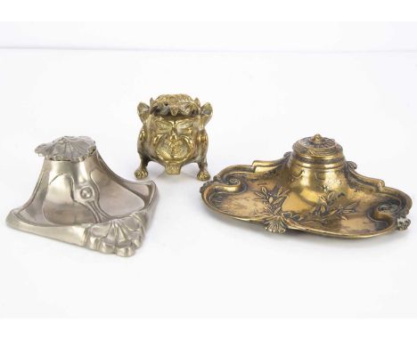 Three Victorian and later desk inkwells, including a brass model of a demon, a pewter example and a brass inkwell with pen tr