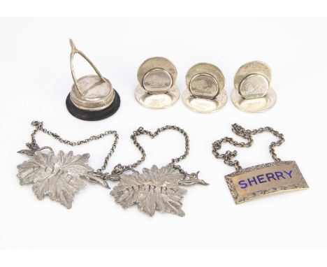 Three silver decanter labels and four place name holders, including a pair of leaf shaped labels, one for Sherry and one for 