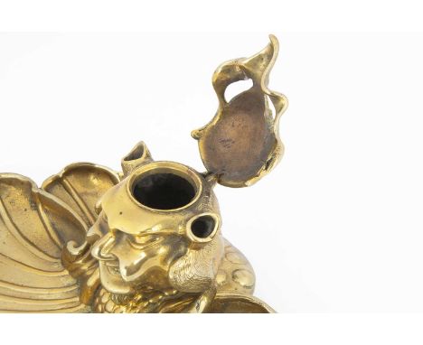 A Victorian brass desk inkwell and pen tray, 22cm wide and 9.5cm high, modelled as a demon with hinged face mask on shell sty