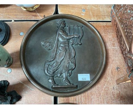 Circular bronze wall plaque decorated in relief with a classical figure playing a lyre. 