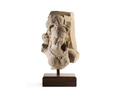 A BUFF SANDSTONE FRAGMENTARY FEMALE BUST, CENTRAL INDIA, 10TH/11TH CENTURY probably depicting Usha shooting an arrow to dispe