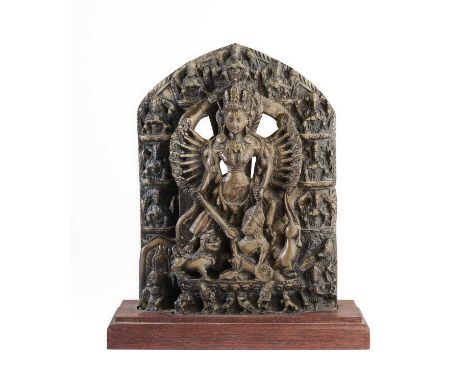 A GREENISH GREY STONE RELIEF DEPICTING DURGA MAHISASURAMARDINI, NEPAL, 18TH/19TH CENTURY  of arched form, the multi-armed god