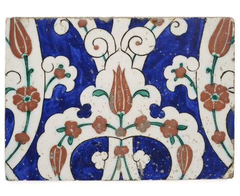 AN IZNIK TILE, OTTOMAN ANATOLIA, CIRCA 1580  underglaze painted fritware, of rectangular form, with reserved white scrolling 