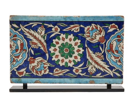 A Rectangular Damascus Iznik Border Tile, Ottoman Syria, 16th century, the central stylized floral bloom amidst foliated flor