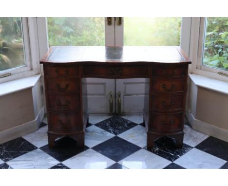 A Georgian style mahogany kneehole desk, serpentine front, central drawer flanked by two sets of four drawers, on bracket fee