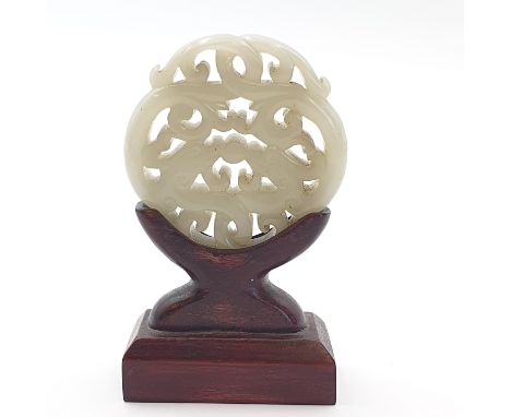 A Chinese Carved Jade Pendant on stand, approx 45mm diameter Hairline crack to edge, see photos. Otherwise no visible damage.