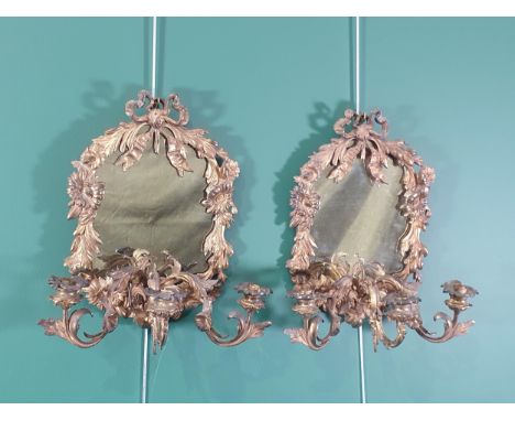A pair of gilded metal girandole Mirrors with designs of ribbon surmounts and shaped oval frames in the form of flowers and l