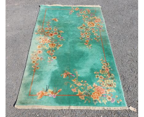 A Chinese Art-Deco Carpet with butterflies and blossoms in an asymmetric design on a jade green field, 6ft 10in x 3ft 10in