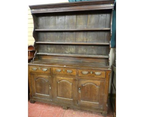 A LATE 18th/EARLY 19th CENTURY OAK DRESSER having a three shelf rack with shaped sides over a base having three opening top d