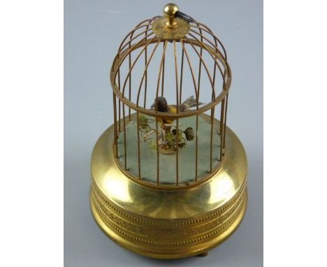 A SUNLEY BIRD AUTOMATON, a single caged bird with moving beak and tail feathers on a circular gilt repousse brass base, wind-