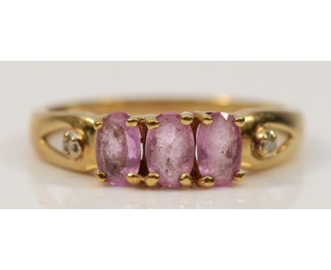 A 9ct gold pink sapphire three stone ring with diamond set shoulders, K, 1.5g
