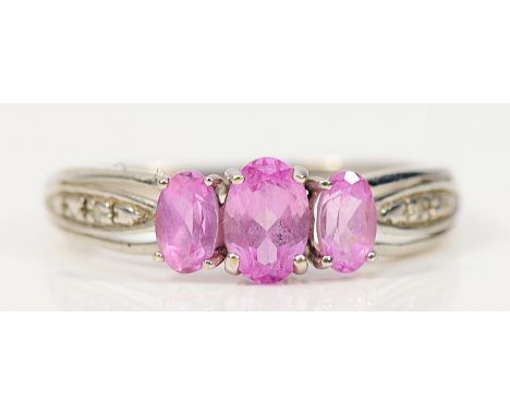 A 9ct white gold pink sapphire three stone ring with diamond set shoulders, O, 2g