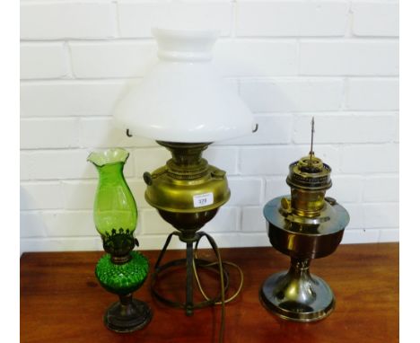 An oil lamp base converted to electricity with a white opaque glass shade, together with another and a small green glass oil 