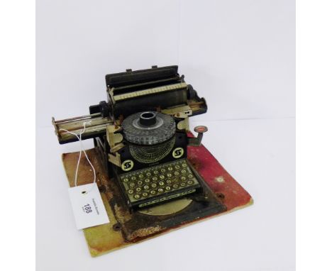 A tin plate toy typewriter, stamped made in Germany, DRP, USA, Patente, mounted on a cardboard base, 18 x 20cm
