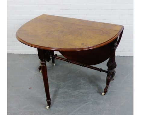 A burr walnut drop leaf table on foliate carved supports terminating in ceramic castors,  76 x 107cm 