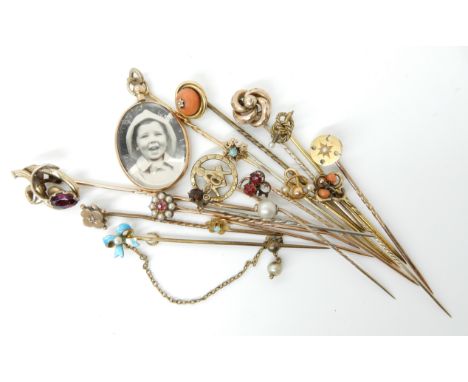 A collection of gold and yellow metal stick pins to include a 9ct locket example, others with enamel, pearls, opals, red gems