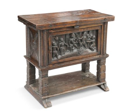 AN OAK CUPBOARD, the rectangular top with twin hinged leaves, above a panelled door deeply carved with figures, raised on car