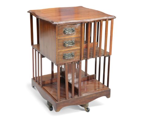 AN ART NOUVEAU MAHOGANY REVOLVING BOOKCASE, with shaped square moulded top and fitted with three drawers with stylised copper