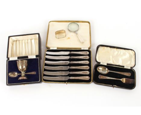 A cased silver Christening fork and spoon; a cased egg cup and spoon; a set of six silver handled tea knives; a silver handle