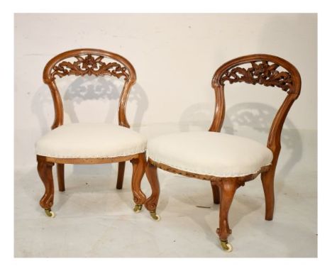 Pair of Victorian walnut framed nursing chairs, each with leaf carved open back, on French cabriole front legs and ceramic ca
