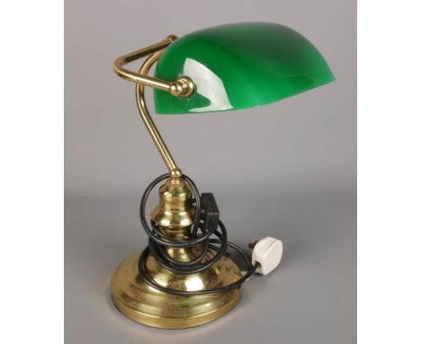 A brass desk lamp with green glass shade.  