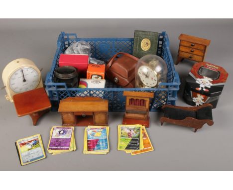 A box of collectables. Including Agfa and Kodak cameras, PokÃ©mon cards, torsion clock, doll house furniture, etc.  